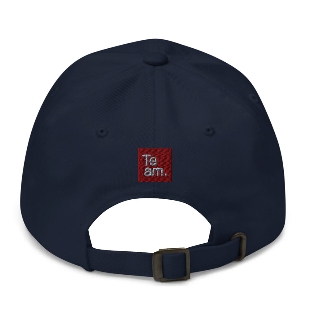 A navy blue baseball cap shown from the back, featuring a small red square embroidered patch with the text 'Team.' in white, and an adjustable strap with a metal buckle.